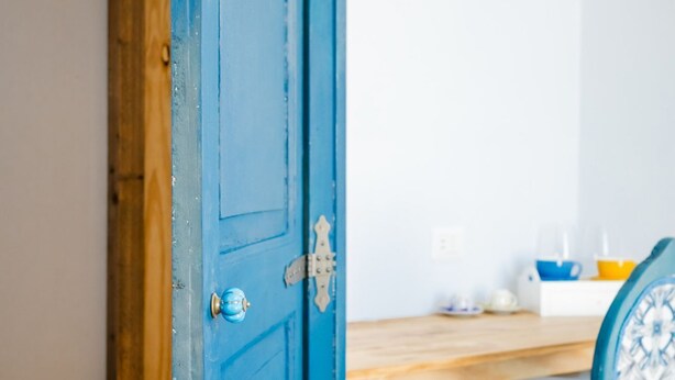 Una puerta azul con un cierre de metal, un marco de madera y un pomo redondo pequeño.