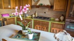 A kitchen with wooden cabinets, a white countertop, and a table with a decorative tray holding potted plants. - Suite Orchidea by Dimorra (Napoli)