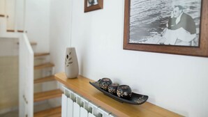 A staircase with a wooden handrail and a white wall with framed photographs. - Suite Orchidea by Dimorra (Napoli)