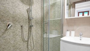 A modern bathroom with a glass-enclosed shower, a white sink, and a marble-patterned wall. - Neapolitan Soul 1 By Dimorra (Napoli)