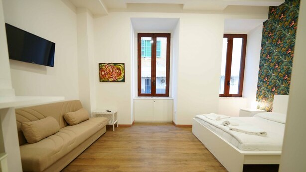 A bedroom with a bed, a sofa, a TV, and a window. - Neapolitan Soul 1 By Dimorra (Napoli)