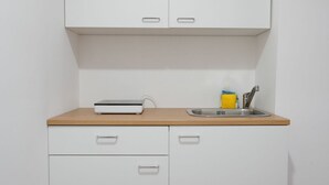 Een keuken met witte kastjes, een houten aanrecht, een spoelbak en een klein apparaat.