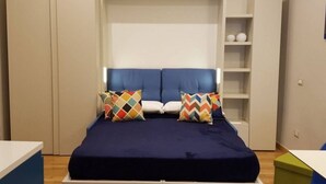 Ein Schlafzimmer mit einem Bett, einem Kleiderschrank und einer kleinen Regalwand.