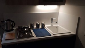 Eine Küche mit einem Gaskochfeld, einer Spüle und einem Wasserkocher.