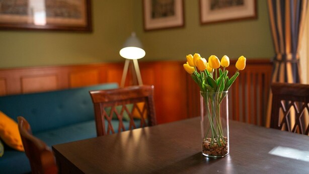 A dining table with a clear glass vase containing yellow tulips. - Sweet Toledo by Dimorra (Napoli)
