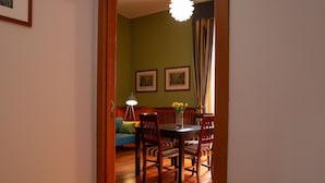 A dining area with a wooden table and chairs, a vase with flowers, and two framed pictures on the wall. - Sweet Toledo by Dimorra (Napoli)