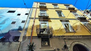 A multi-story building with balconies, a large mural on the facade, and a visible door. - Sweet Toledo by Dimorra (Napoli)