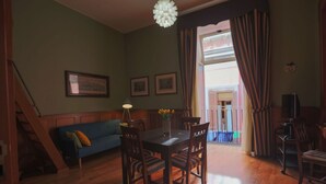 A dining area with a wooden table and chairs, a vase with flowers, and a staircase leading to another room. - Sweet Toledo by Dimorra (Napoli)
