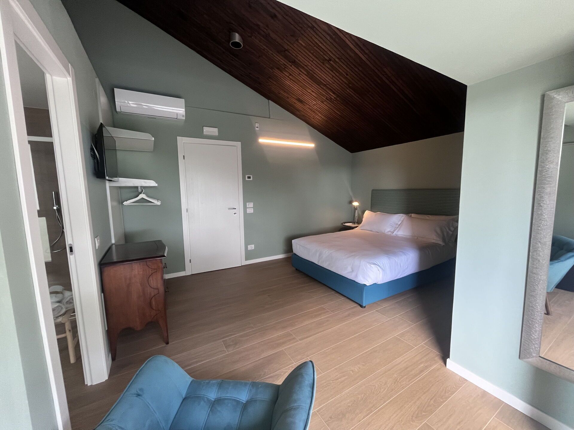 Een slaapkamer met een bed, bureau, stoel en kledingkast.