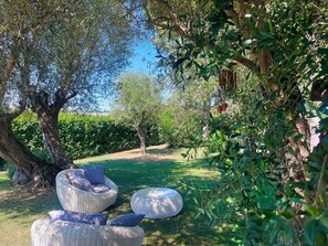 A garden with a wicker sofa and ottoman, surrounded by trees and a hedge. - Private Villa with A/C, private pool, sauna, WIFI, TV, patio, panoramic view, close to Rimini (Santarcangelo Di Romagna)