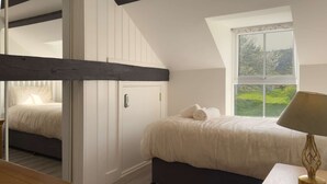 Une chambre à coucher avec un lit, une fenêtre donnant sur un beau paysage, une table de chevet et une lampe.