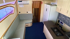 Cocina compacta con estufa, microondas y refrigerador pequeño. Se observa una ventana con vista al agua.