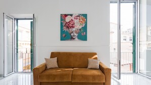 Ein modernes Wohnzimmer mit einem braunen Sofa, einem großen Fenster und einem floralen Kunstwerk an der Wand.