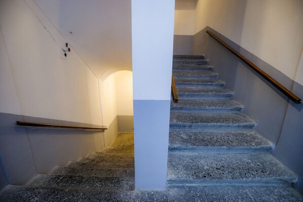 A staircase with a wooden handrail and a white wall on one side. - The Games Apartment By Dimorra (Napoli)
