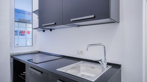 Cuina moderna amb vàlvula de brossa d'acer inoxidable, taulells negres i armaris grisos.