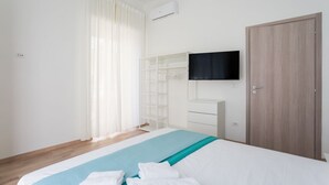 A bedroom with a bed, a TV mounted on the wall, a wardrobe, and a window with curtains. - Metro Station By Dimorra (Napoli)