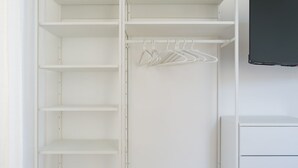 A white closet with multiple shelves and a hanging rod. - Metro Station By Dimorra (Napoli)