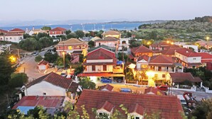 Une ville côtière avec des maisons aux toits rouges, une route bien visible et une étendue d’eau en arrière-plan.