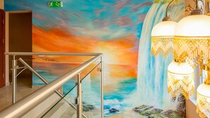 A staircase with a glass railing leading to a room with a mural of a waterfall and a mural of a sunset. - Beautiful apartment in Pobierowo with WiFi (Pobierowo)