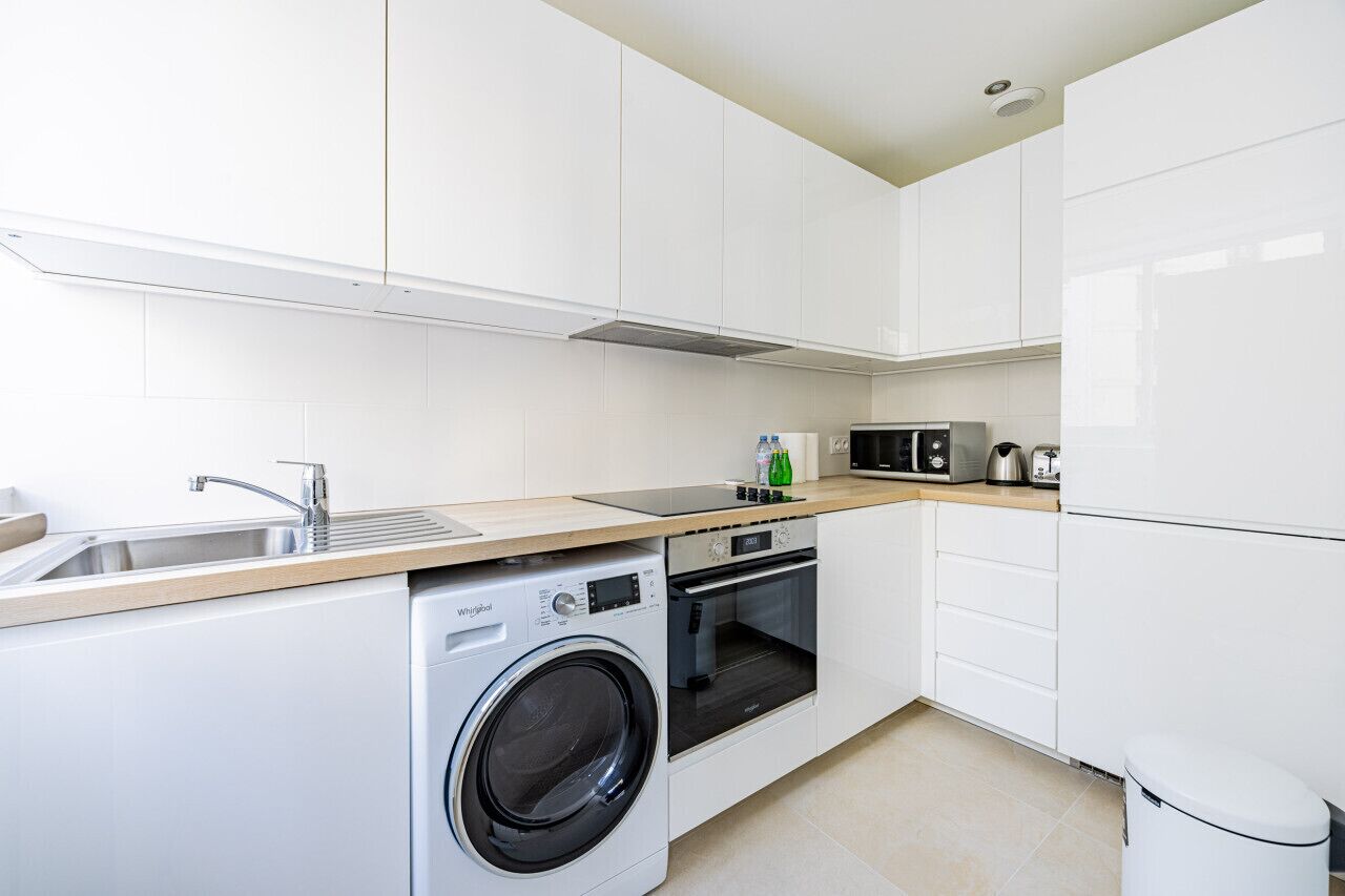 A modern kitchen with a built-in washer, oven, microwave, and a sink.