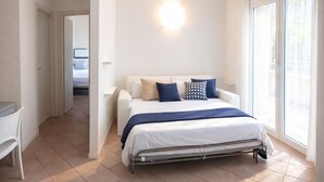 A bedroom with a bed, a desk, and a window with curtains. - Li Velieri 6 pax Pool & Private Garden (Santa Teresa Gallura)