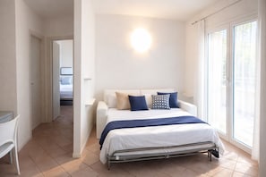 A bedroom with a bed, a desk, and a window with curtains.