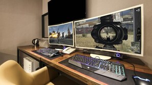 Un equipo de juego con dos monitores, un teclado y un ratón sobre un escritorio de madera.