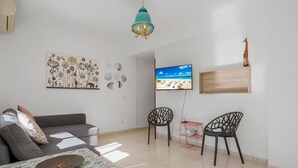 A living room with a sofa, two chairs, a coffee table, a TV, and a wall-mounted shelf with a giraffe figurine. - Bright Rooftop in Fuengirola City Center by Costarentals - Ref 255 (Fuengirola)