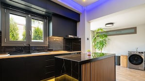 Eine moderne Küche mit schwarzen Schränken, einer Holztischinsel und einer integrierten Waschmaschine.