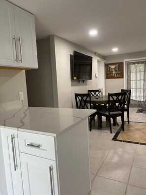 A modern kitchen with white cabinets, a marble countertop, and a dining area with a table and chairs. - 
Private 5-Acre Retreat in Rustic Ranches with Modern Country Comfort (Wellington)