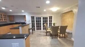 A spacious kitchen with a dining area, featuring a large island, built-in cabinets, and a view through French doors. - 
Private 5-Acre Retreat in Rustic Ranches with Modern Country Comfort (Wellington)