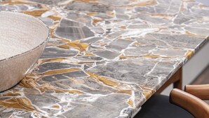 Una mesa de comedor con cubierta de mármol y sillas con acolchado negro.