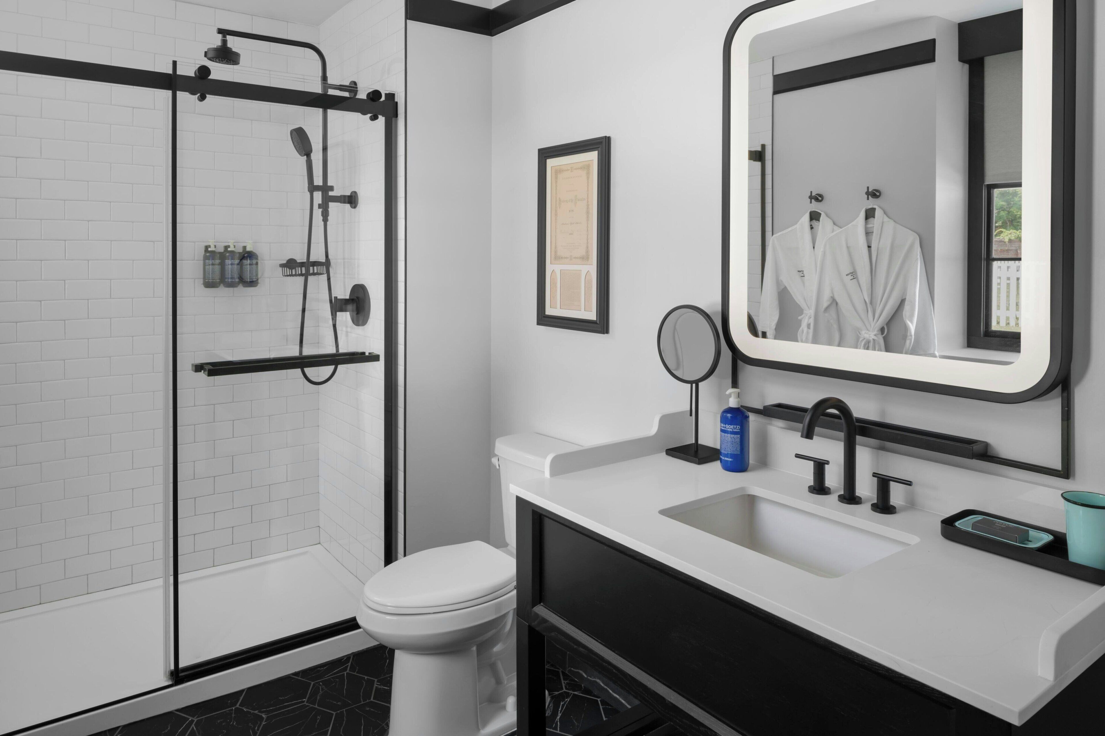 Un baño moderno con ducha, inodoro, lavamanos y un espejo grande.