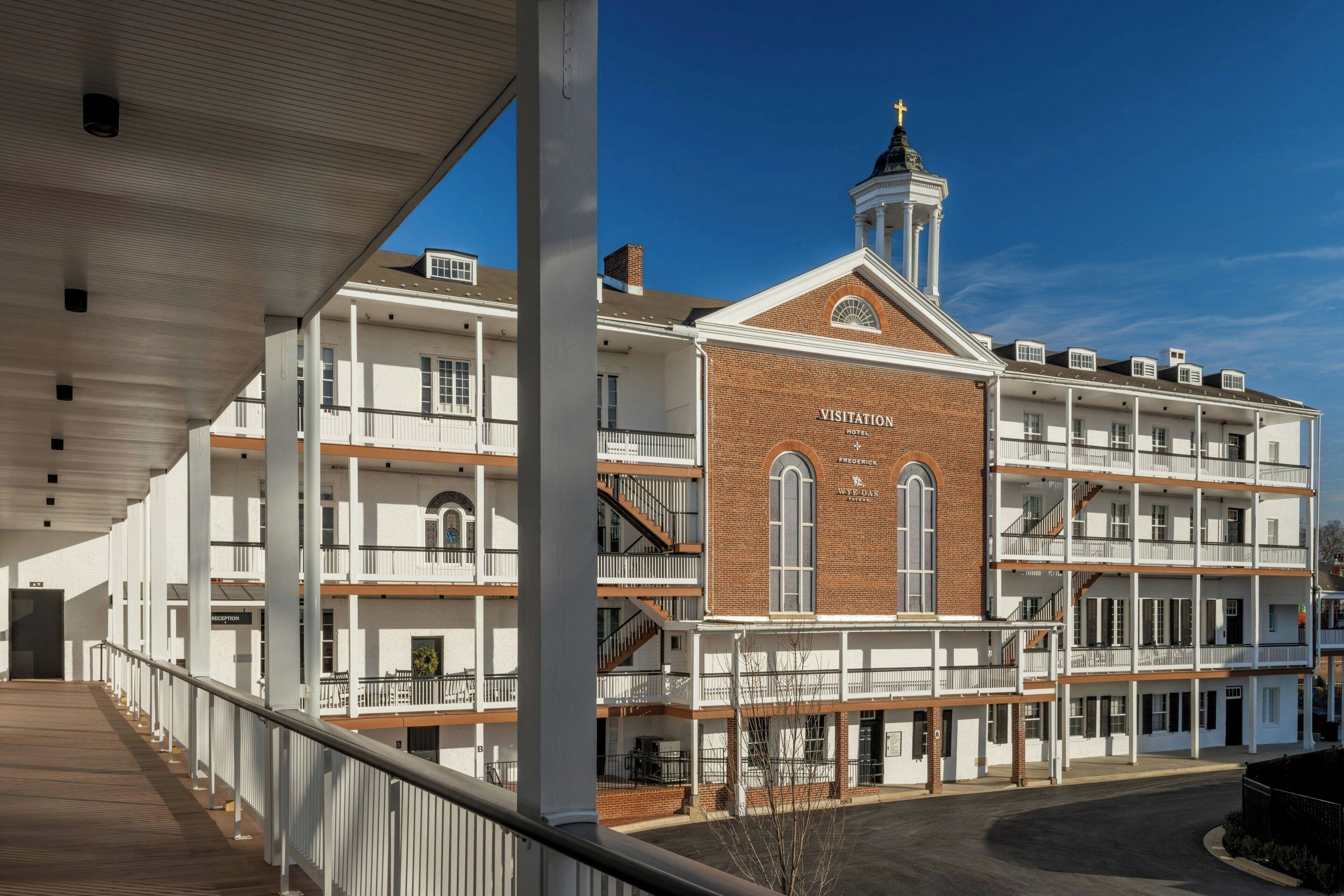 A multi-story hotel with a prominent entrance, a covered walkway, and a bell tower.