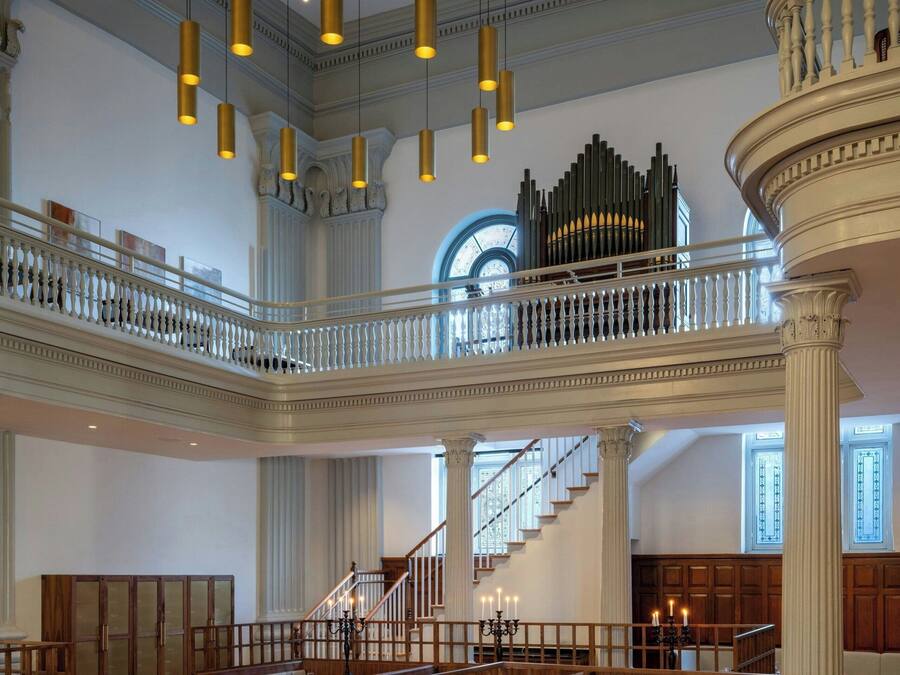 A spacious dining area with high ceilings, chandeliers, and a grand staircase.