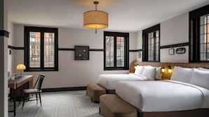 A hotel room with two beds, a desk with a chair, and a large window with black frames. - Visitation Hotel Frederick, a Tribute Portfolio Hotel (Frederick)