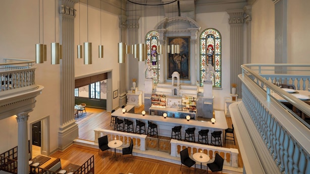 A spacious hotel lobby with a bar area, seating arrangements, and a staircase. - Visitation Hotel Frederick, a Tribute Portfolio Hotel (Frederick)
