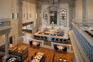 A spacious hotel lobby with a bar area, seating arrangements, and a staircase. - Visitation Hotel Frederick, a Tribute Portfolio Hotel (Frederick)