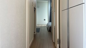 A narrow hallway with a bed at the end, a door on the right, and a light fixture on the ceiling. - BE Terrace Nishi-Shinjuku _Shinjuku Area / 5 min. walk from Nishi-Shinjuku Station 6 min. from Shinjuku Station (新宿区)