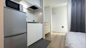 A compact room with a kitchenette, a bed, and a small dresser. - BE Terrace Nishi-Shinjuku _Shinjuku Area / 5 min. walk from Nishi-Shinjuku Station 6 min. from Shinjuku Station (新宿区)