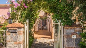 A stone pathway leading to a rustic outdoor seating area with a table and chairs, surrounded by lush greenery and flowering plants. - B&B La Torretta - Double Room with Sea View (Cersuta)