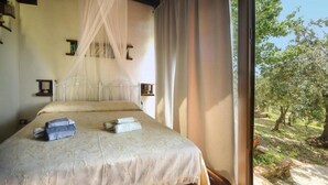 A bedroom with a bed, a canopy, a window, and a view of trees.