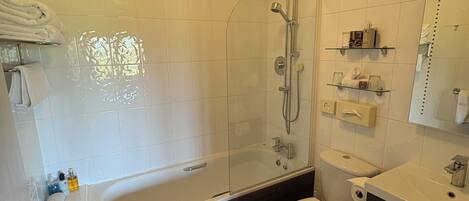 Un baño moderno con ducha de vidrio, bañera, inodoro y tocador con espejo.