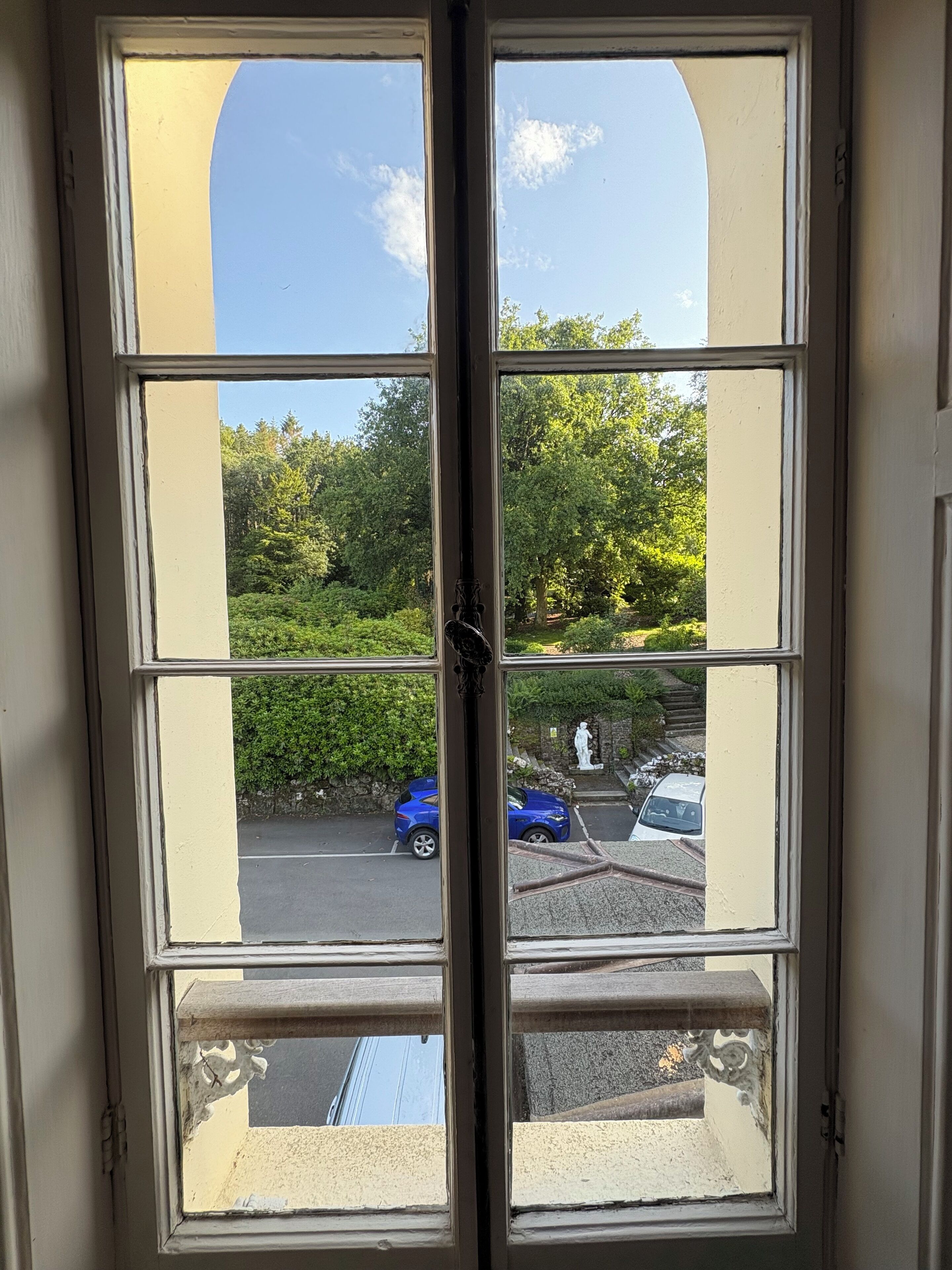 A window with a view of a parking area and greenery outside.