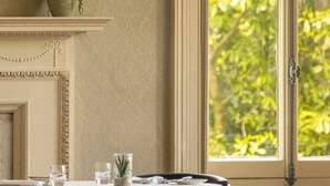 Ein Essbereich mit Tisch für zwei Personen, einer Blumenvase und einem Fenster mit Blick auf Grünfläche.