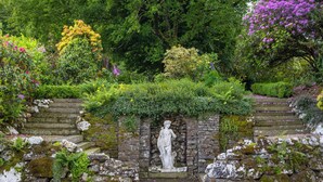 Eine Steinstatue in einem Garten mit einer Steintreppe, die zu ihr hinaufführt.