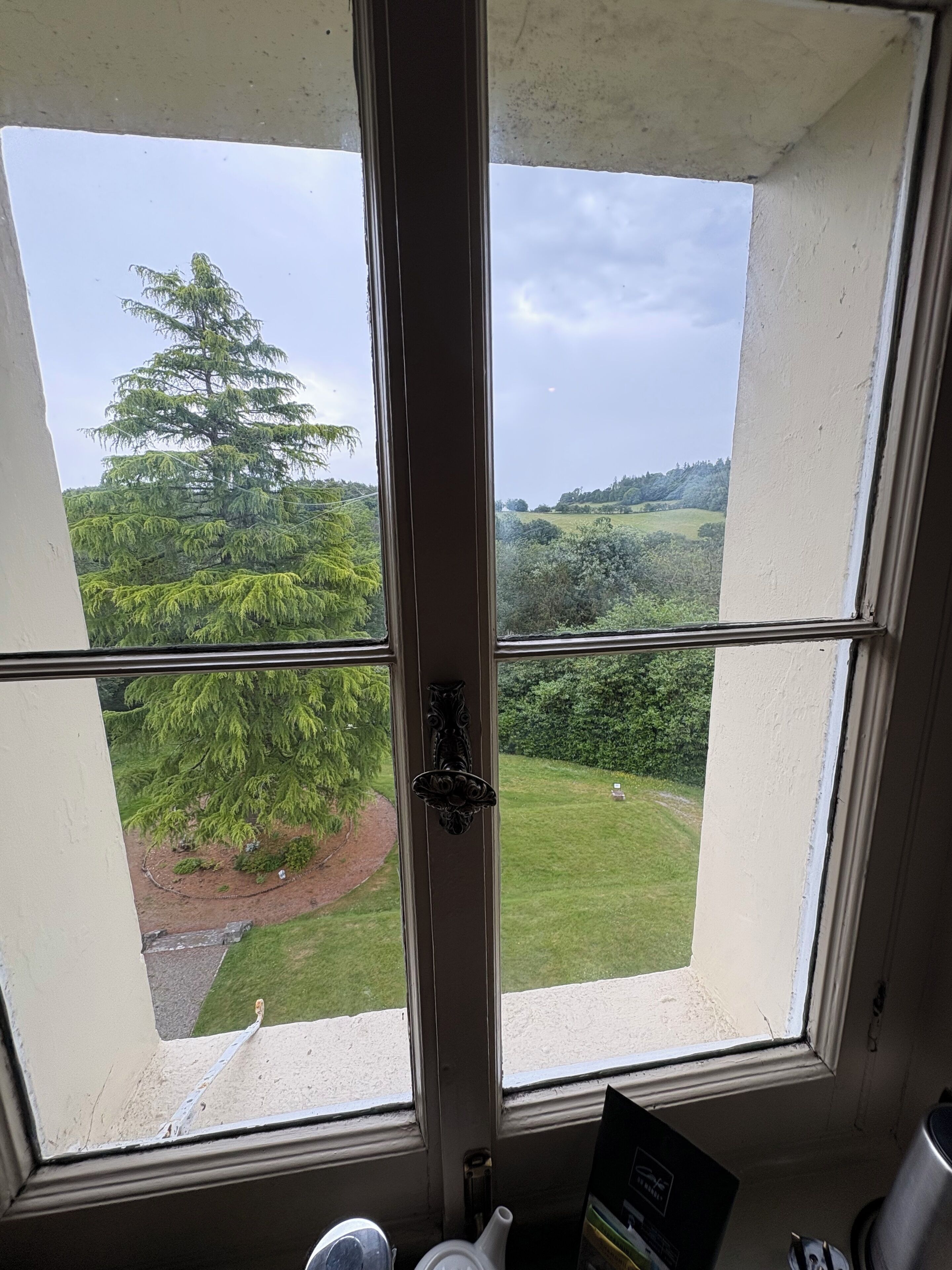 A room with a large window offering a view of a green landscape, including trees and a grassy area.