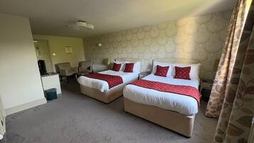A hotel room with two beds, a desk, a chair, and a small table.