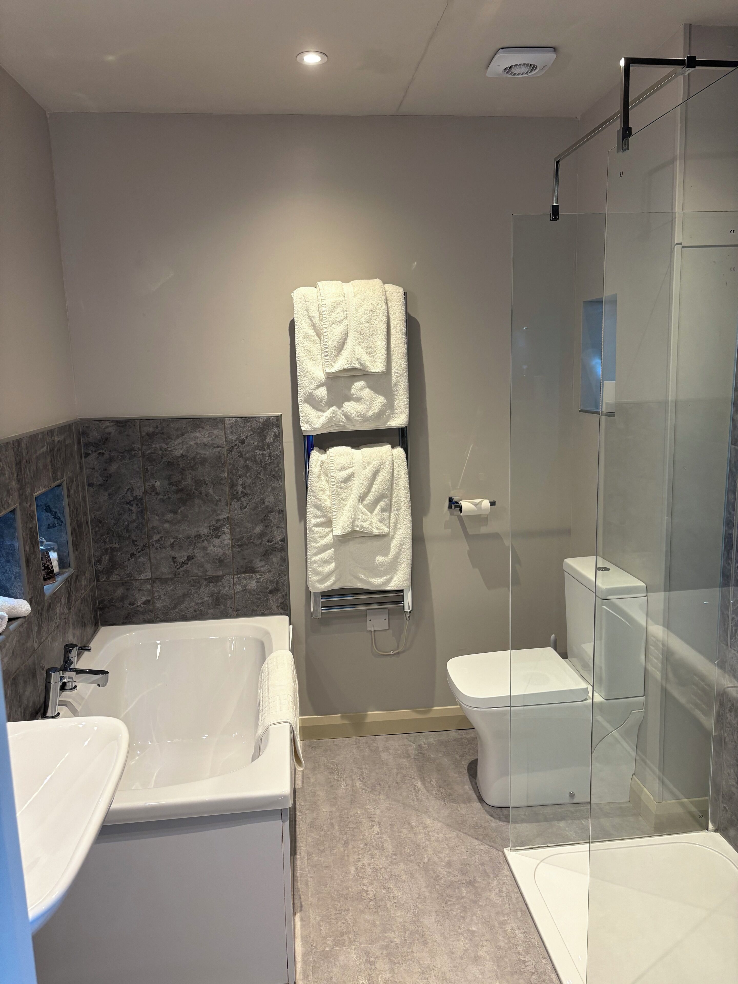A modern bathroom with a glass shower enclosure, a separate toilet, and a freestanding bathtub.
