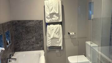 A modern bathroom with a glass shower enclosure, a separate toilet, and a freestanding bathtub.